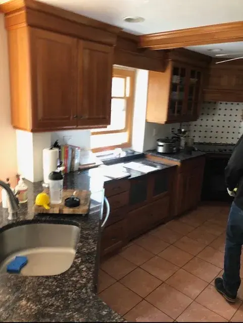 A person standing in the kitchen with a sink.