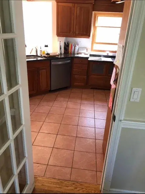 A kitchen with tile floors and wooden cabinets.