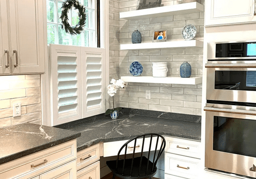 A kitchen with white cabinets and black counter tops.