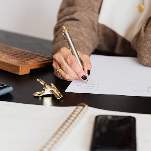 A person writing on paper with a pen.