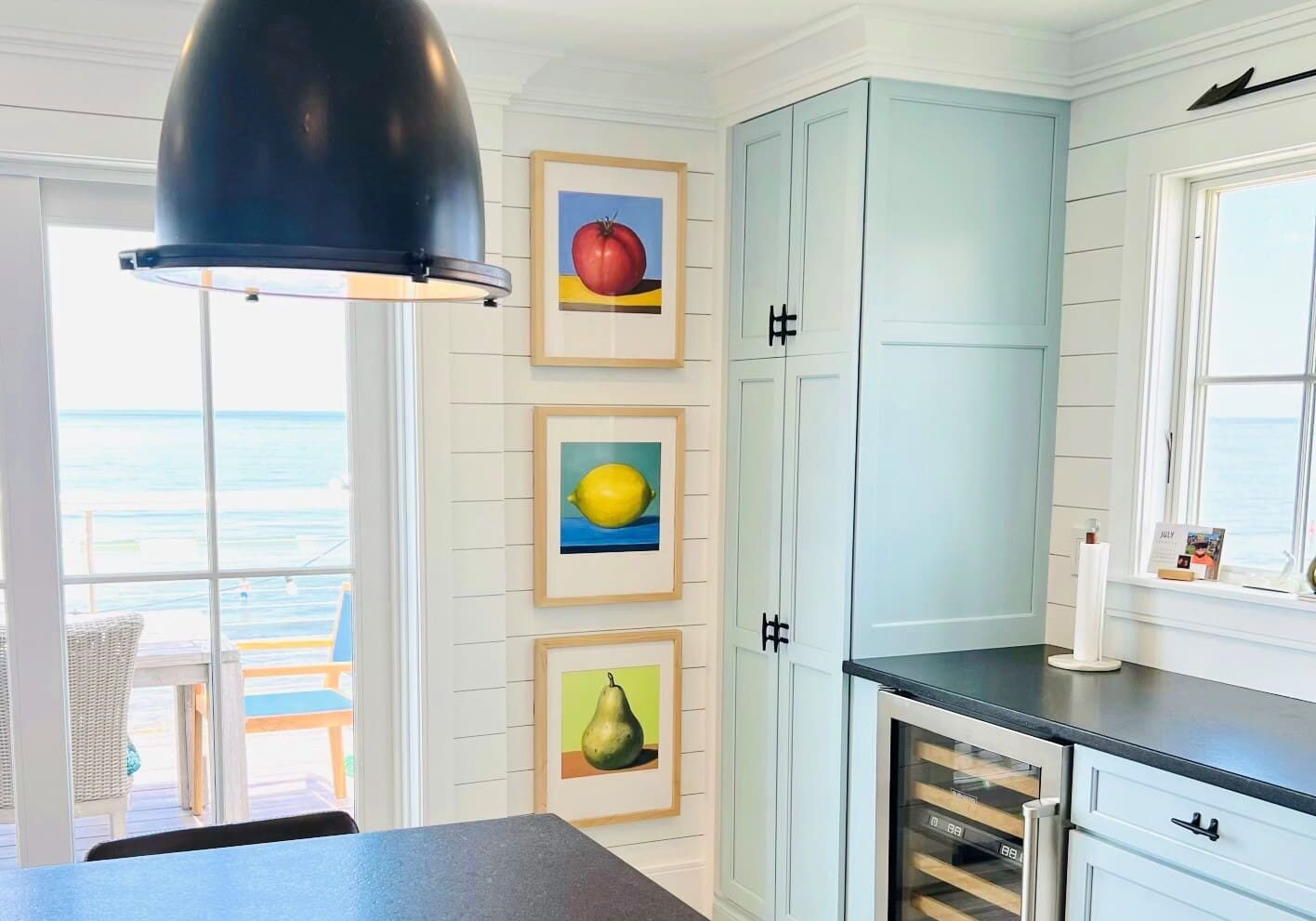 A kitchen with a view of the ocean and a black counter.