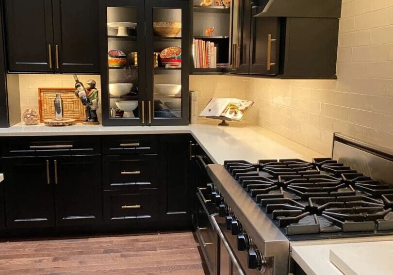 A kitchen with black cabinets and white counters.